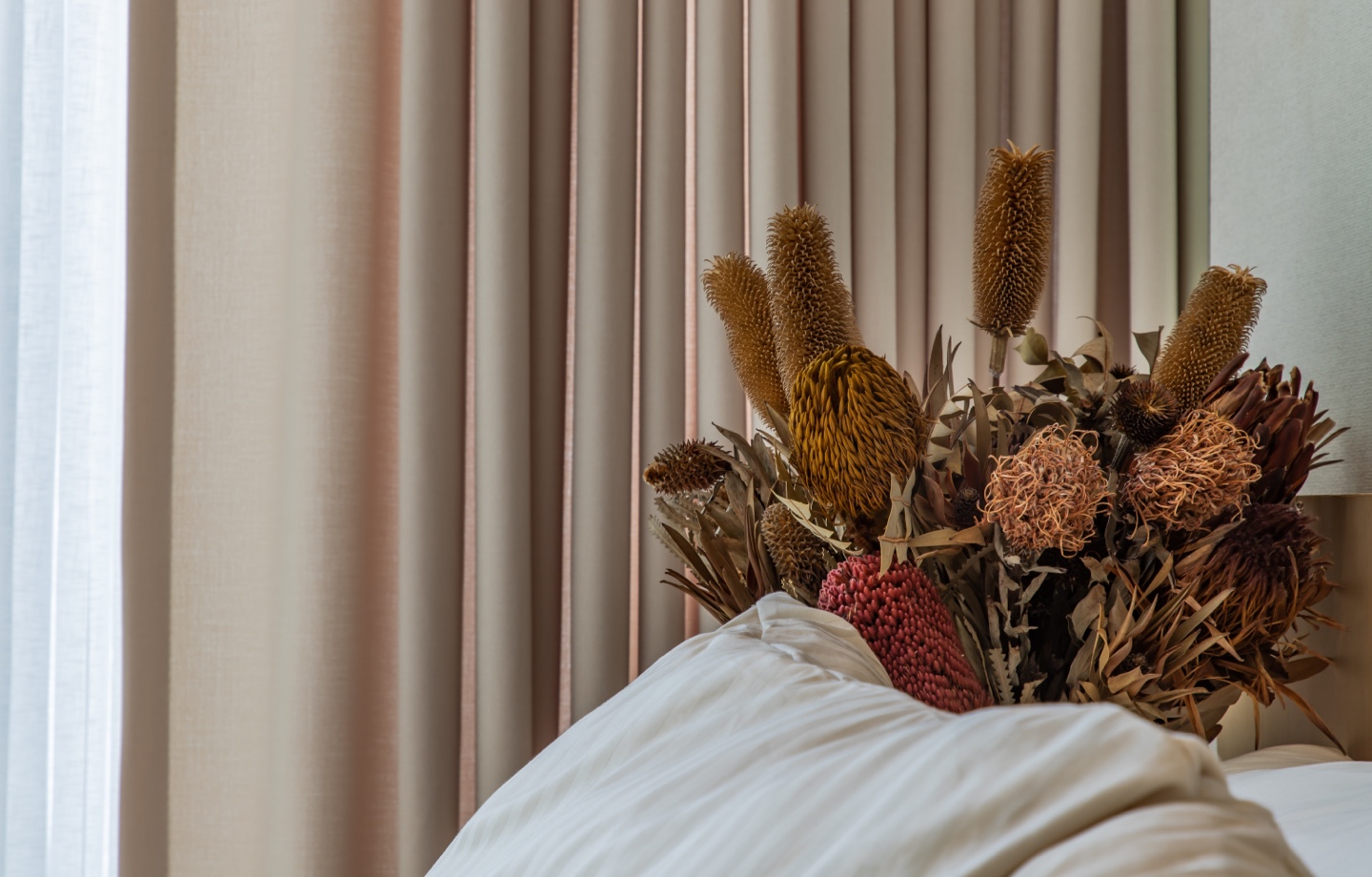 Pillows And Dried Flowers On Nightstand Header