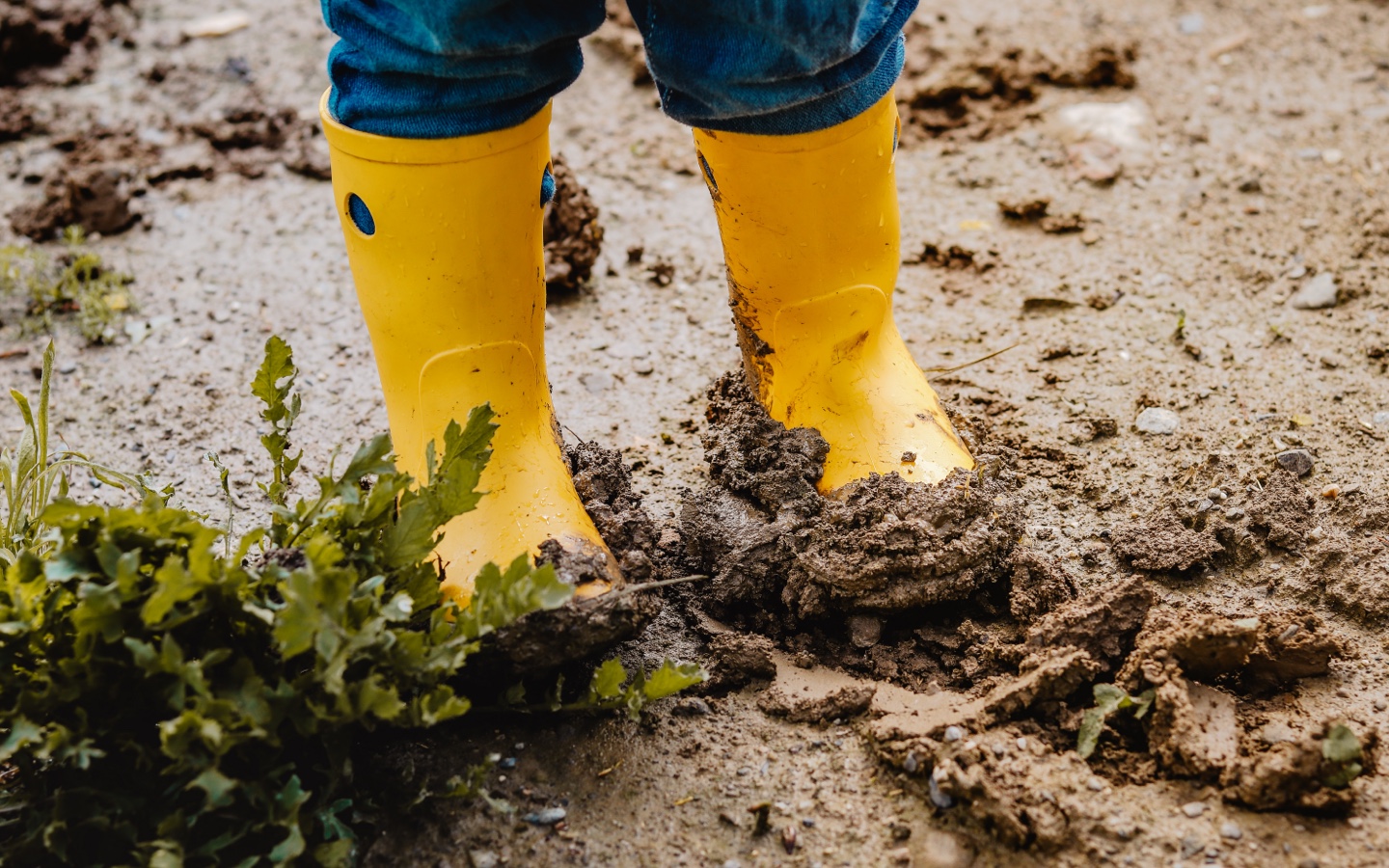 Child Wearing Rain Boots While Playing in Mud