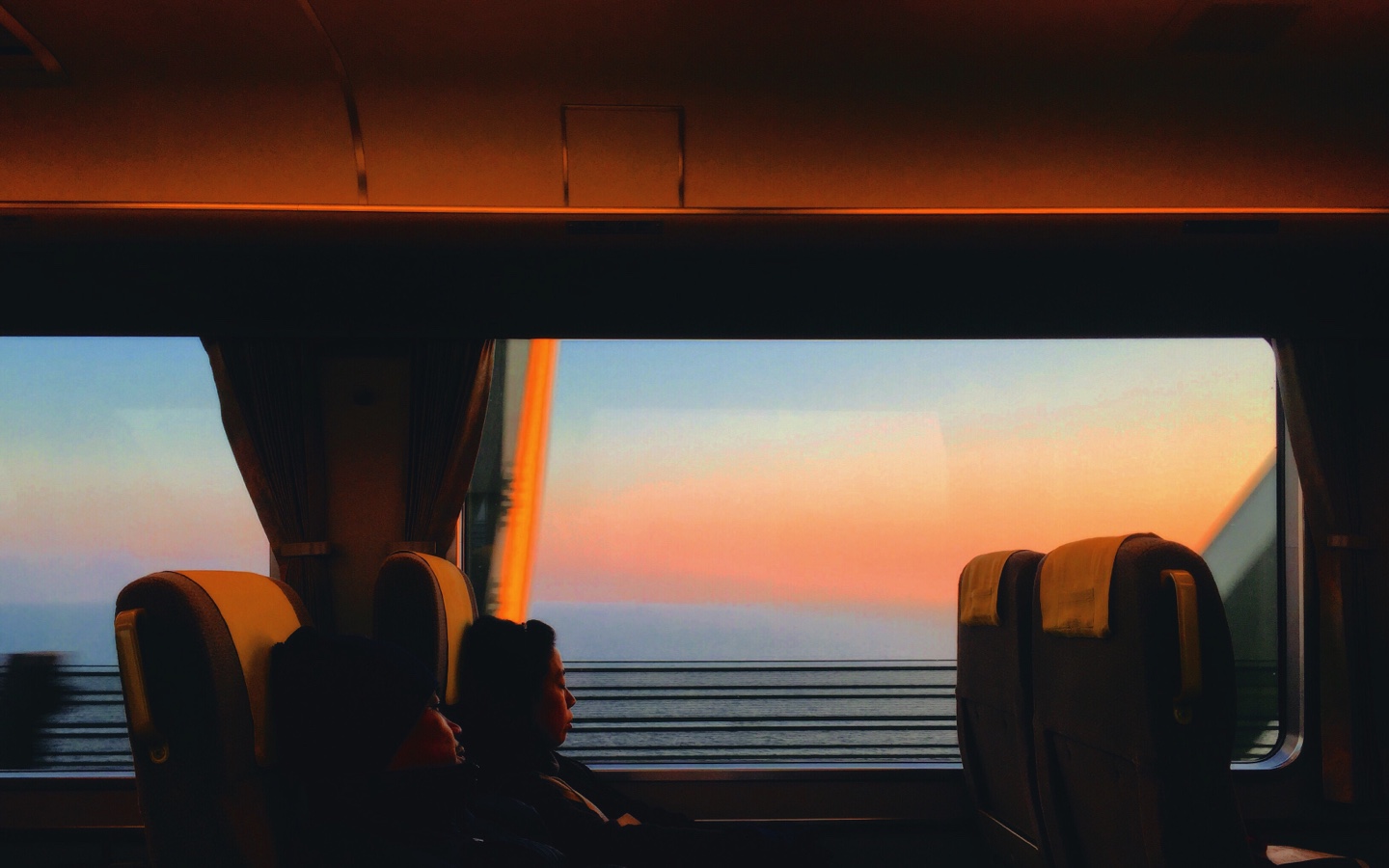 Two People Sitting On A Train At Sunrise