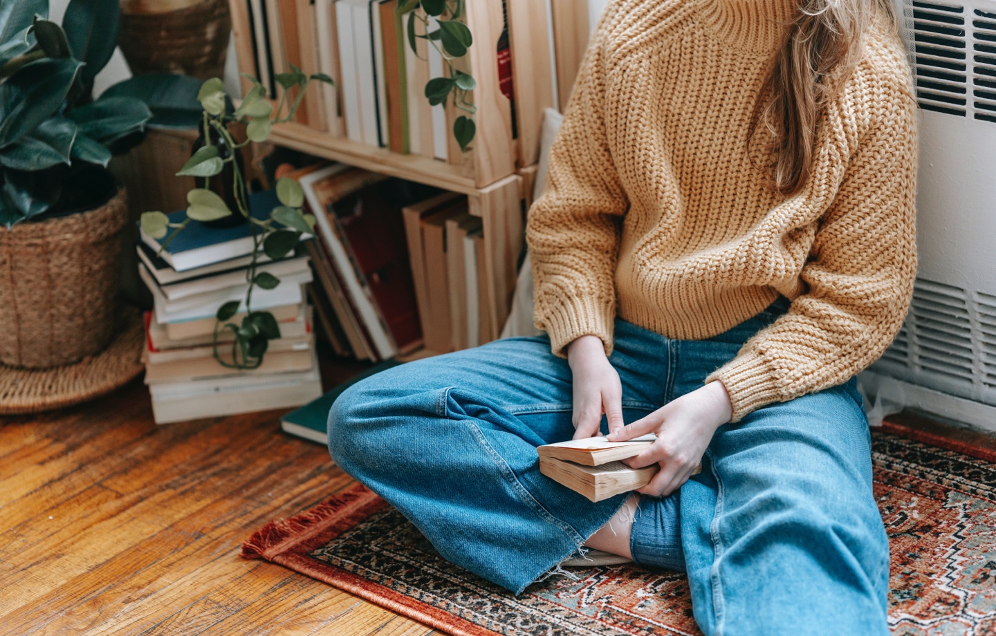woman sitting on the floor by radiator reading