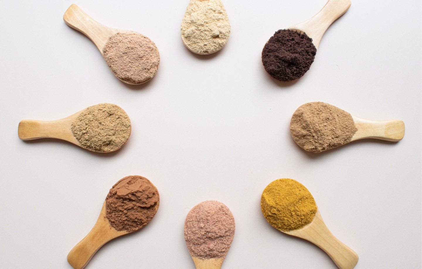 assortment of plant based protein powder on wooden spoons