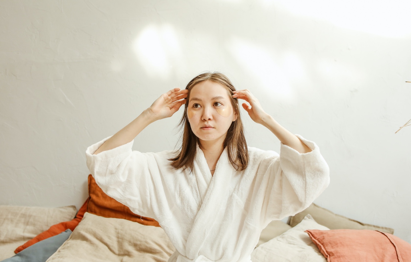 person sitting on bed wearing a robe and eye patches