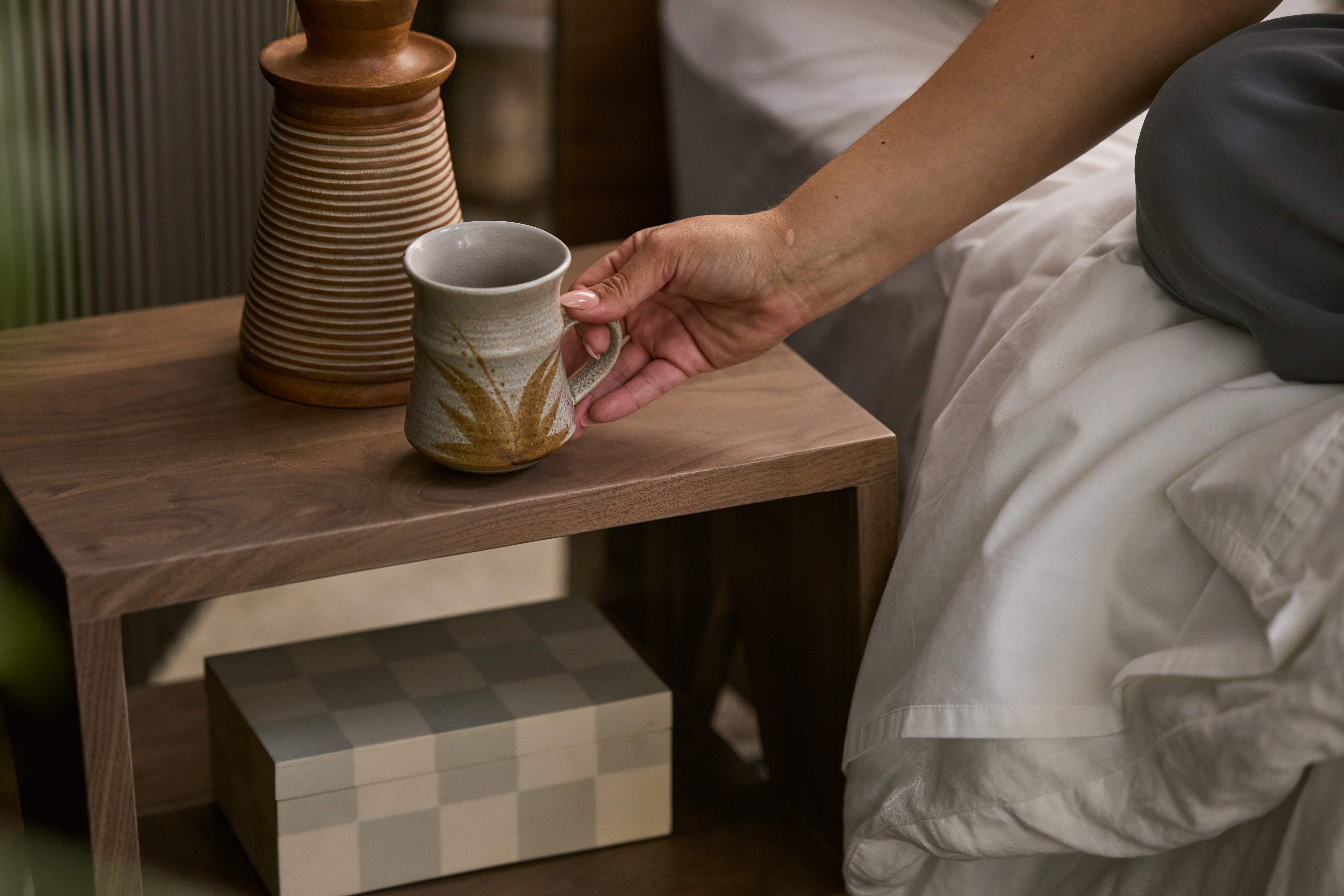 woman placing cup of tea on avocado city nightstand
