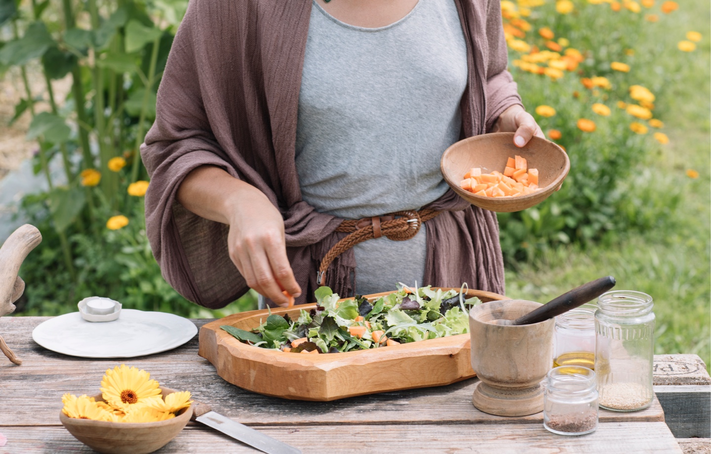 woman making salad with garden greens and edible flowers