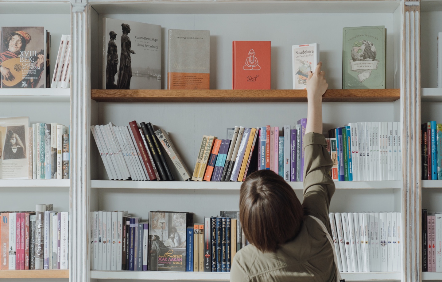 person choosing book of library shelf