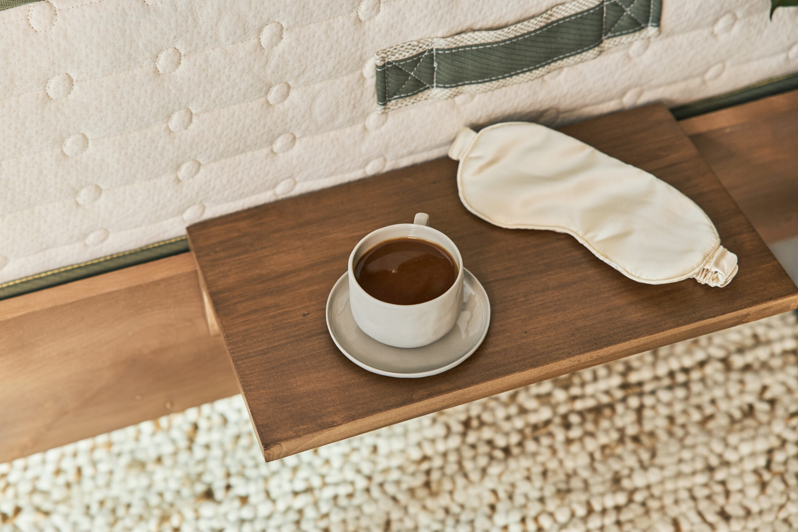 cup of coffee and sleep mask on side table