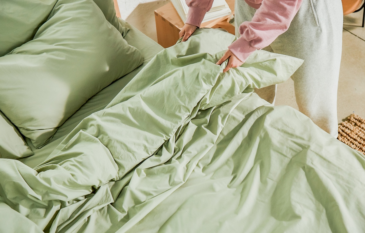 making the bed with avocado percale organic cotton sheets in sage
