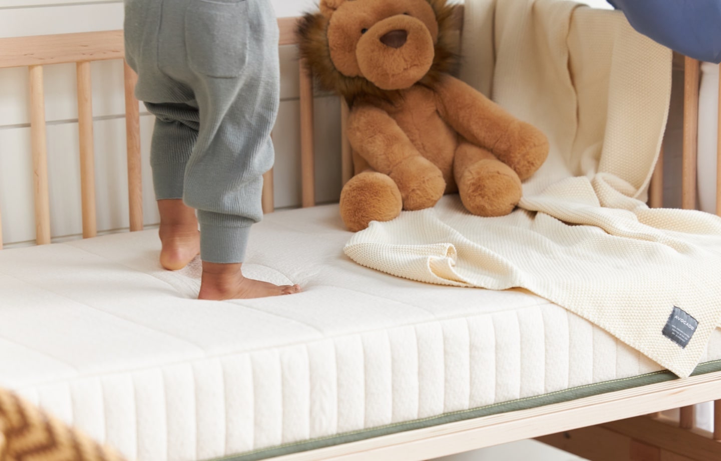 toddler standing on avocado organic crib mattress
