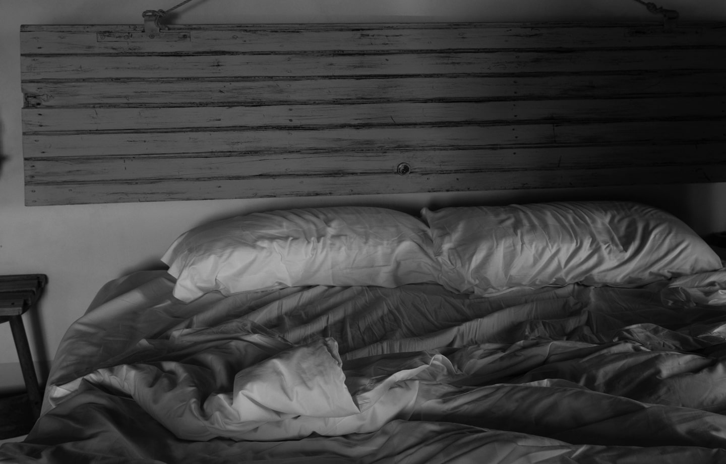 black and white photo of unmade bed in peaceful bedroom