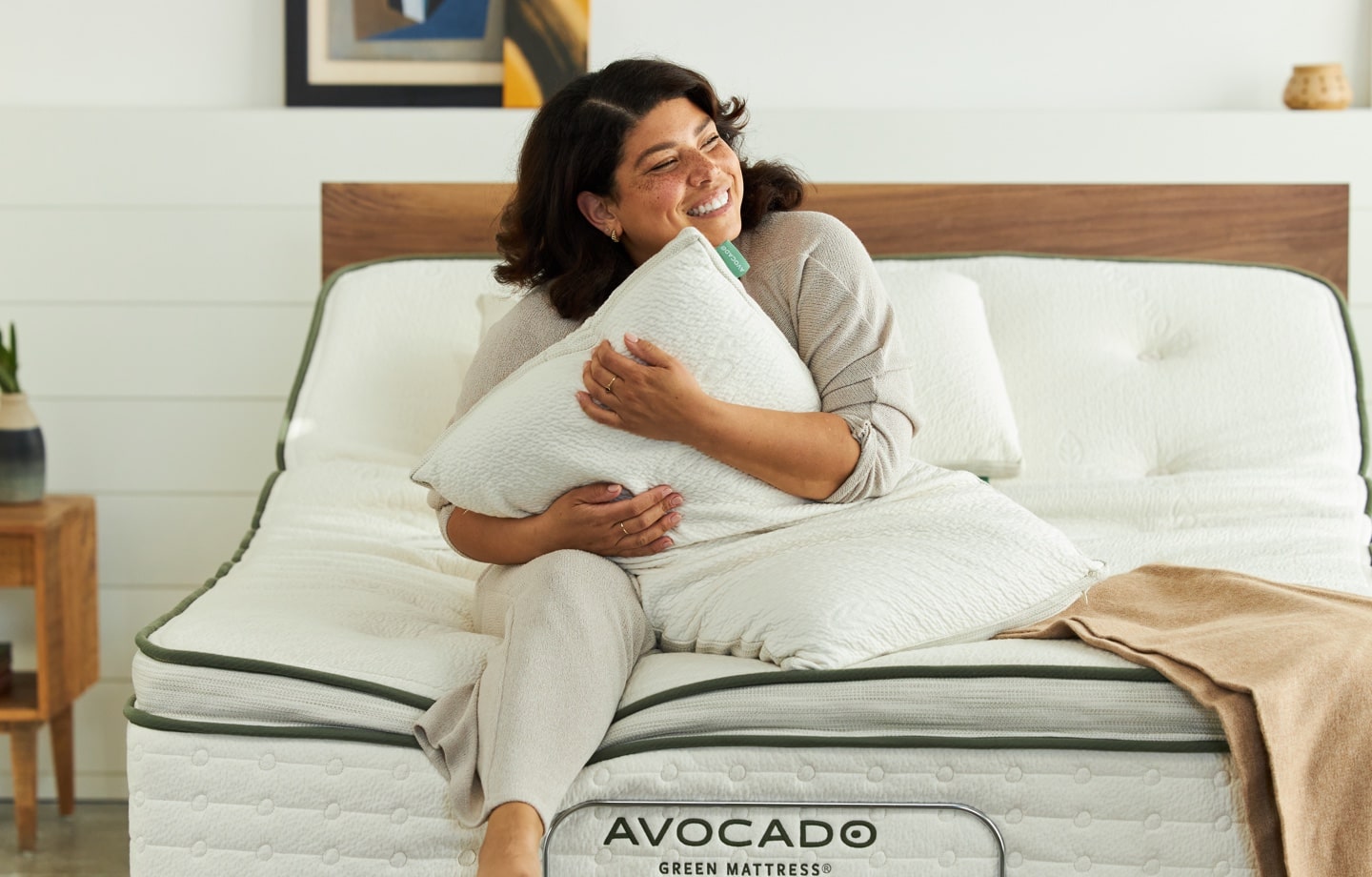 woman sitting on avocado green mattress holding avocado molded latex pillow
