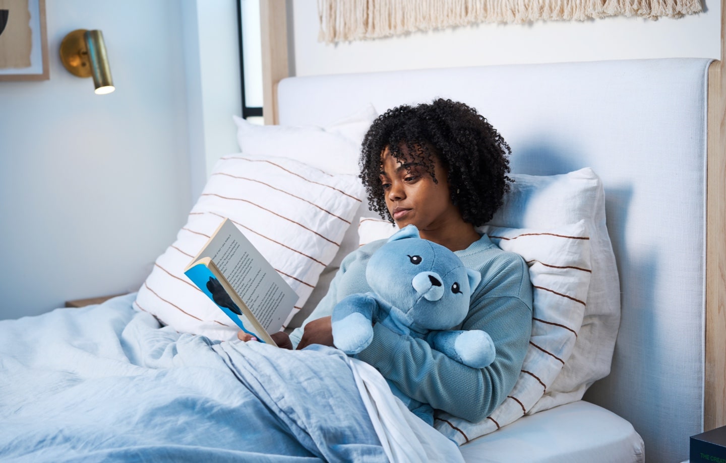 girl reading in bed with hugimals weighted stuffed animal