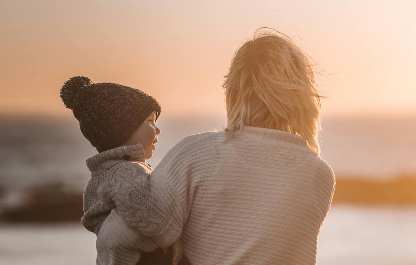 mother holding toddler at the beach