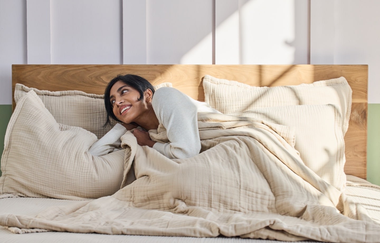 woman lying down covered in avocado organic cotton gauze bedding - ayurveda and sleep