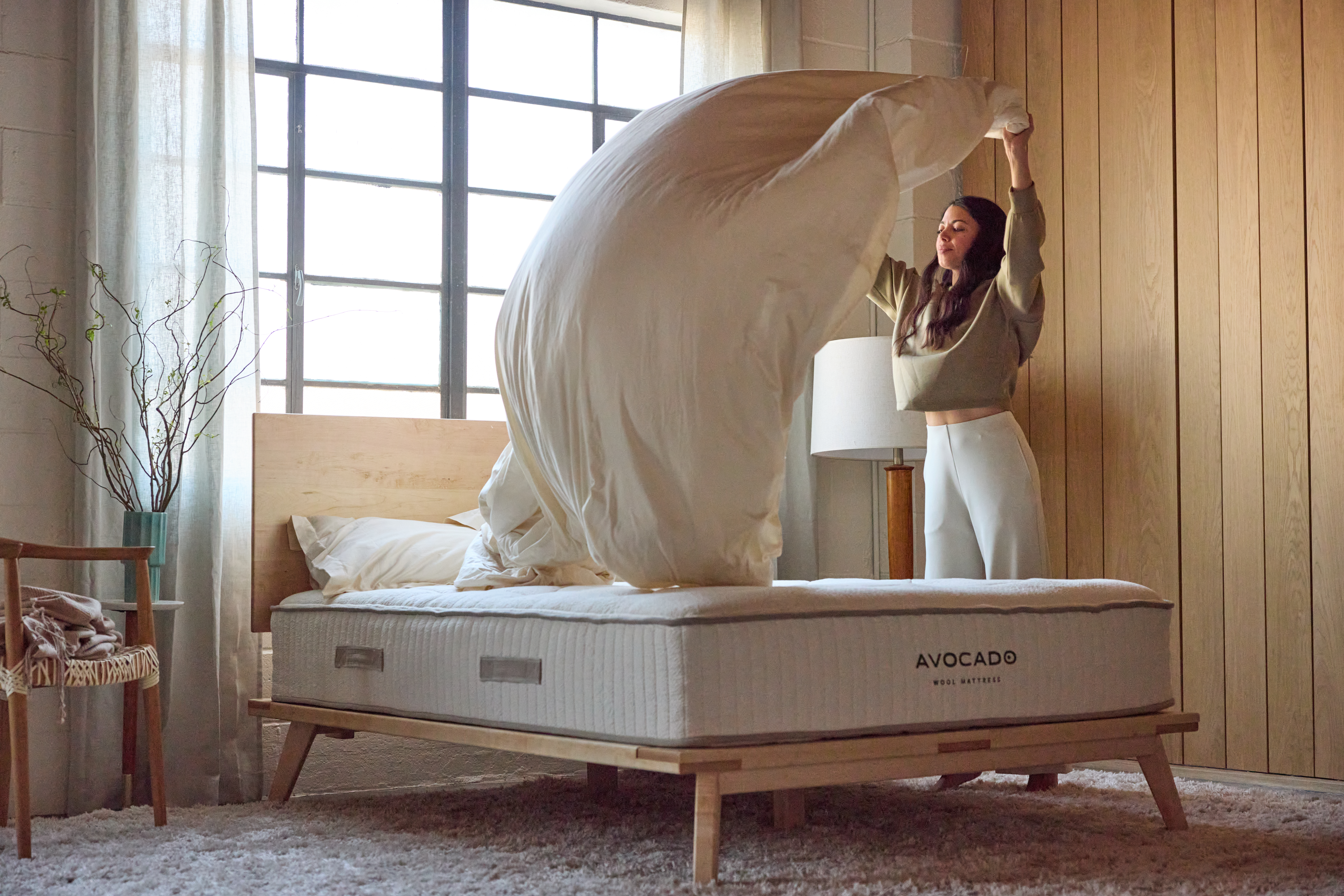 Woman fixing sheets on Wool Mattress