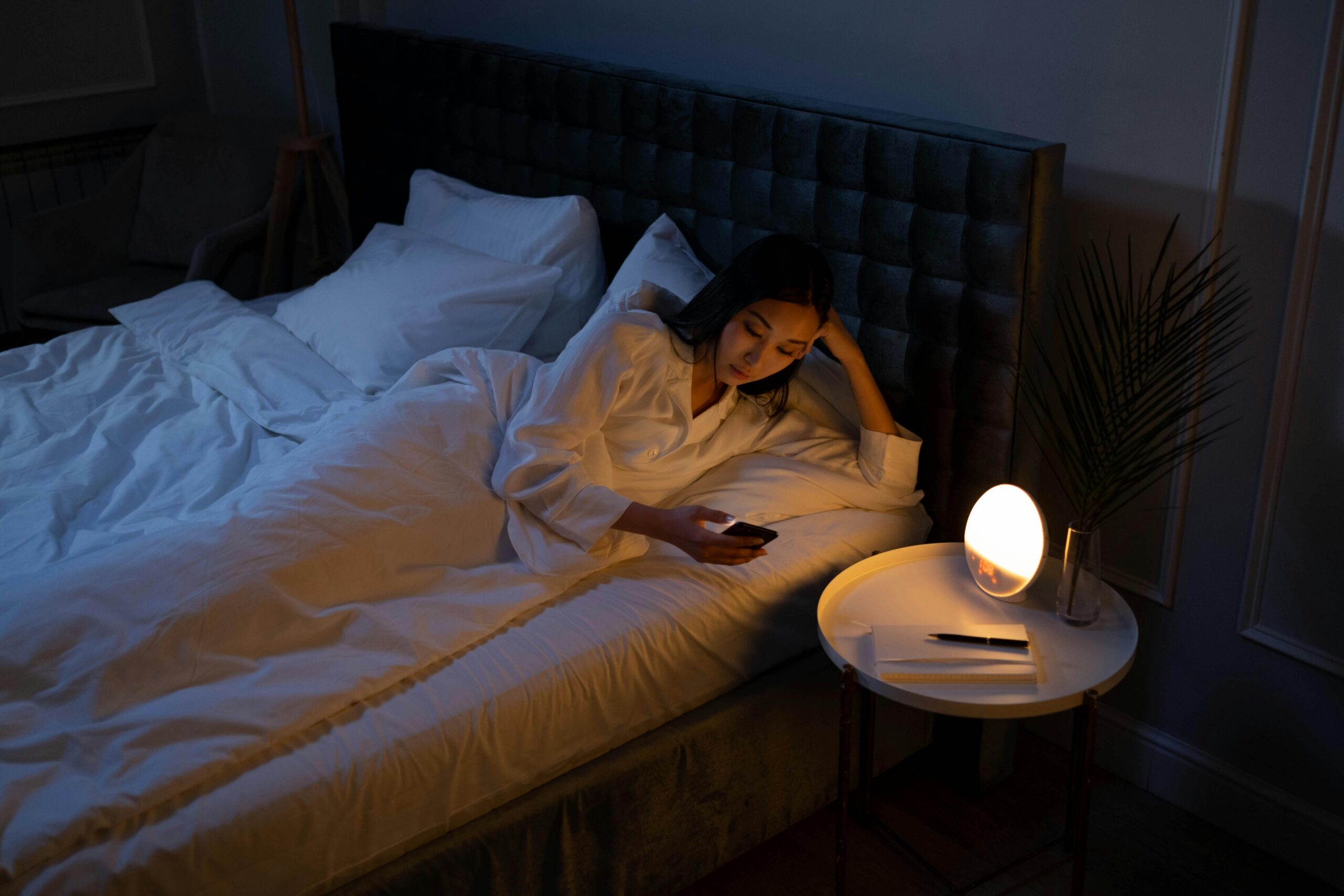 Woman laying in bed looking at her phone