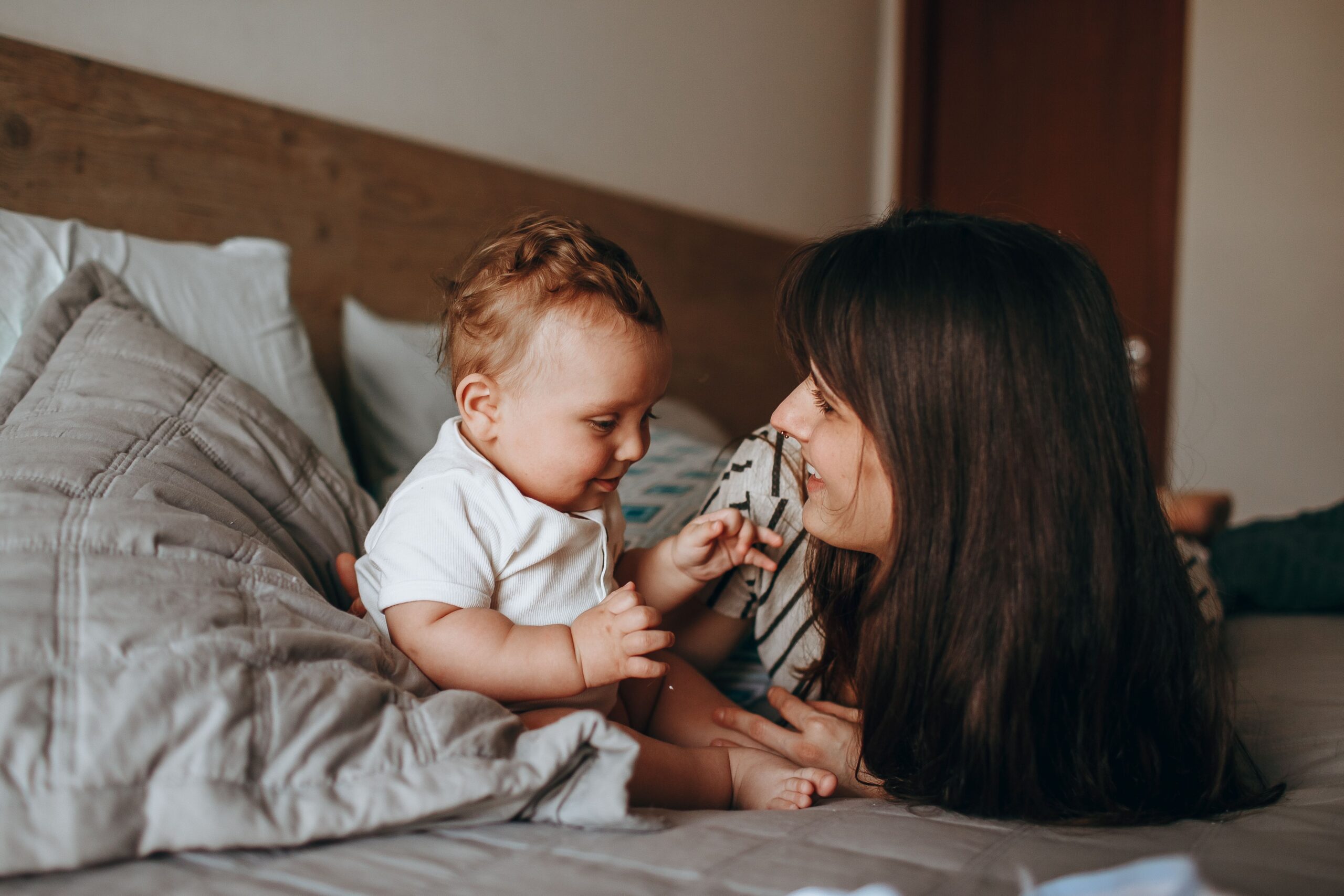 mom and baby sitting on bed